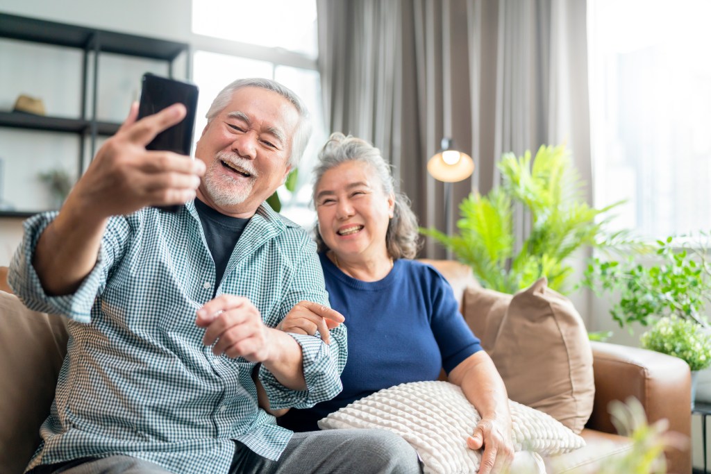 happiness Asian old senior retired couple enjoy videocall to family together on sofa in living room at home,asian people use smartphone communication to family home isolation ides concept