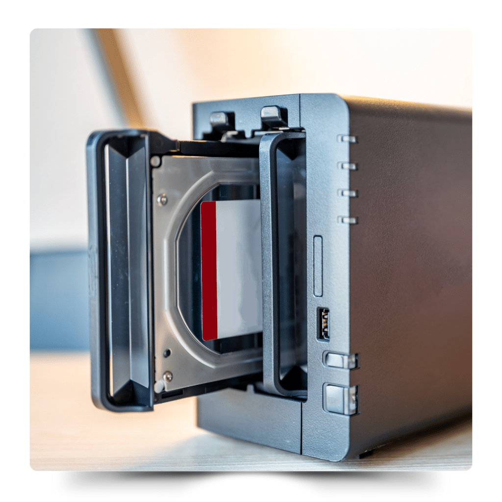 一台 NAS 設備正開啟，展示其中的硬碟插槽，顯示出 NAS 設備的靈活擴展性和硬碟更換的便利性。