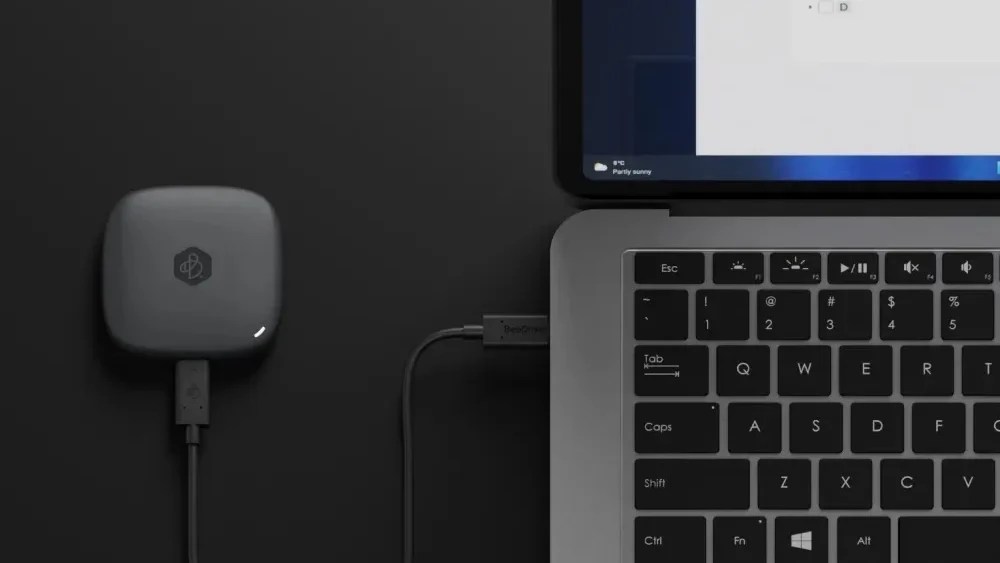 一台黑色的Synology 群暉科技 BeeDrive 2TB 個人行動備份裝置正在與一台銀灰色的筆記型電腦傳輸資料
